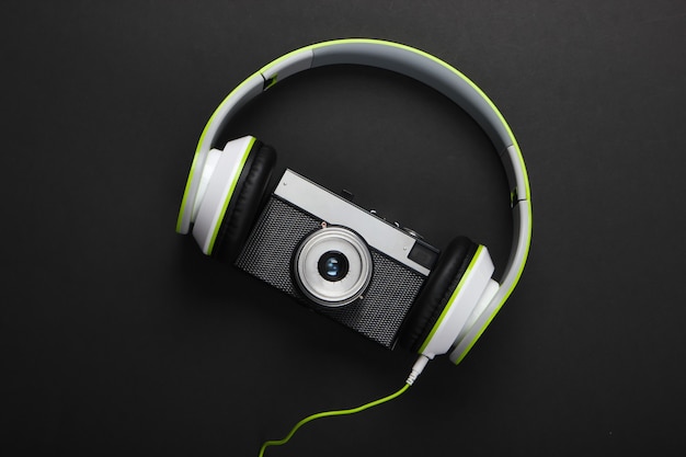 Stylish wired stereo headphones with retro camera on black surface