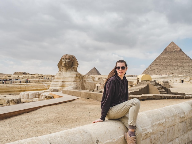 Photo stylish woman against the background of the giza pyramid complex