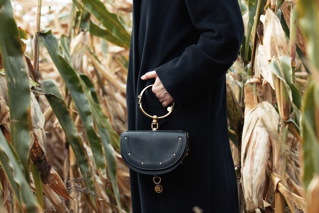 Stylish woman in black coat in autumn corn field