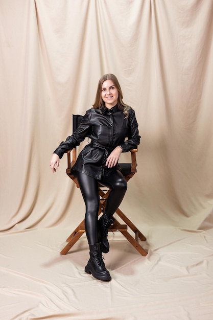 Stylish woman in black leather boots from the new fall-winter 2022 collection. Young woman dressed in a black leather shirt and leggings