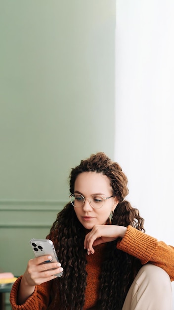 Stylish woman browsing on smartphone at home for online shopping young woman wearing glasses