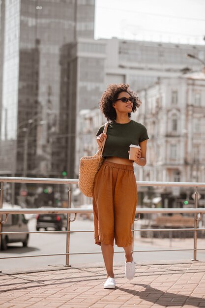 A stylish woman in the city street with a cup of coffee