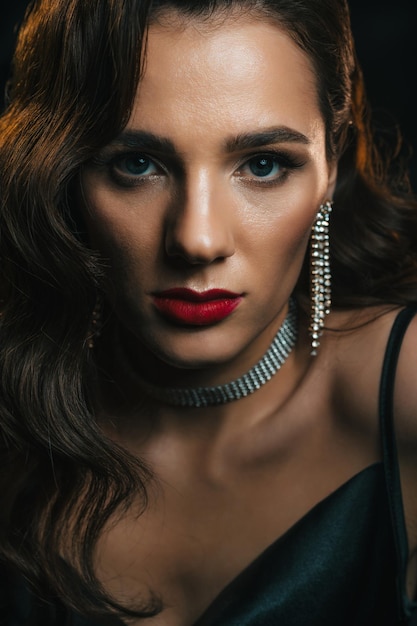 Stylish woman in classic retro style of 1950s Hollywood movies with a beautiful hairstyle and makeup Portrait of girl in vintage look with jewelry on dark background