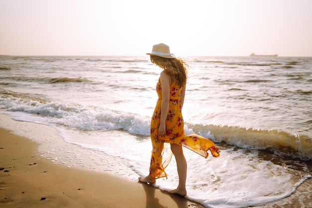 Stylish woman in elegant dress posing near the sea Summer time Travel weekend relax