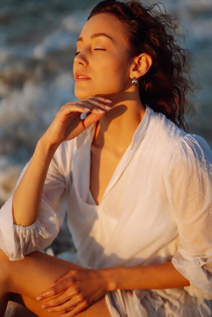 Stylish woman in elegant white dress posing near the sea Summer time Travel weekend relax