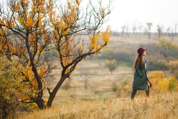 Stylish woman enjoying autumn weather in the meadow