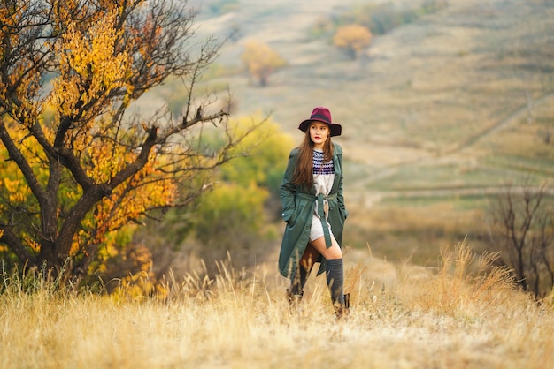 Stylish woman enjoying autumn weather in the meadow