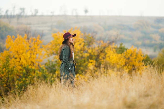 Stylish woman enjoying autumn weather in the meadow