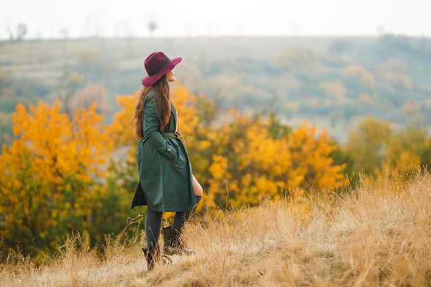 Stylish woman enjoying autumn weather in the meadow