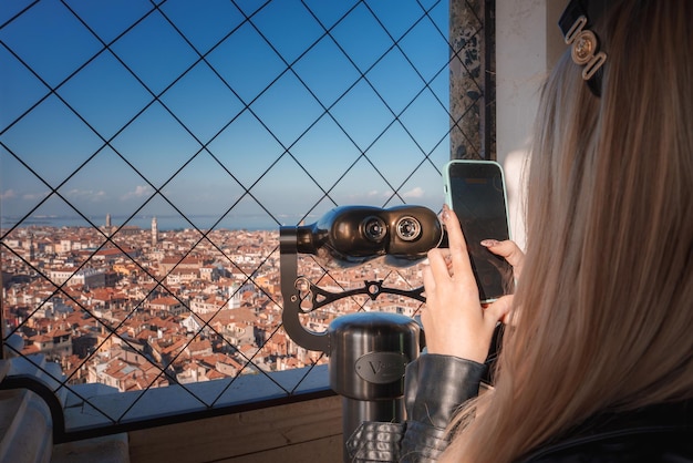 Donna alla moda che si gode una vista ipnotica di venezia attraverso un telescopio