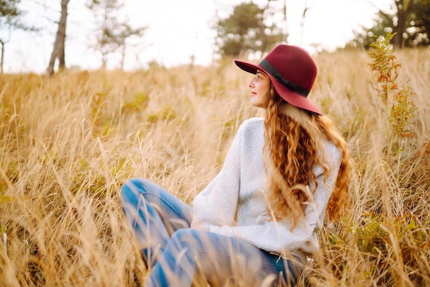 Stylish woman in hat enjoying autumn weather in the park Fashion style concept