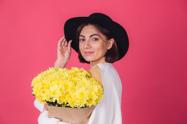 Stylish woman in hat on red wall