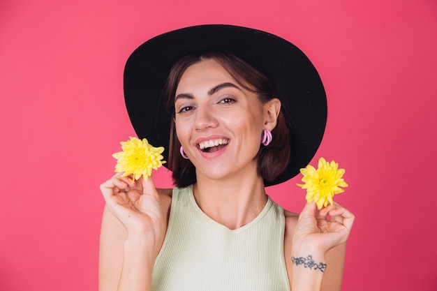 Stylish woman in hat, smiling with two yellow asters, spring mood, happy emotions isolated space