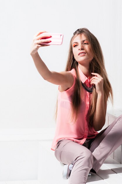 Photo stylish woman making selfie on mobile phone white interior
