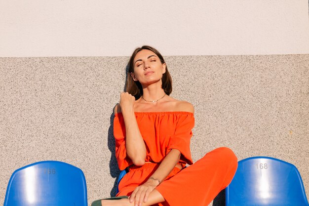 Foto donna alla moda in vestiti arancioni al tramonto alla posa dello stadio della pista ciclabile