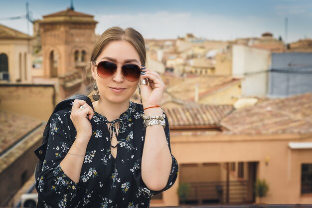 Stylish woman posing in the old part of the town against tile roofs. 