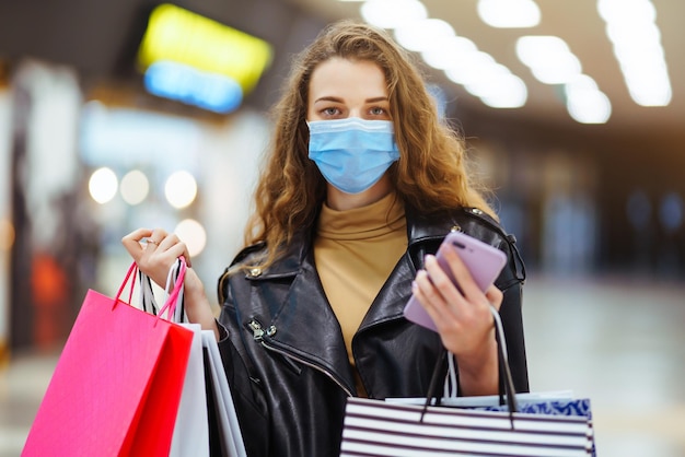 Stylish woman in protective medical mask with shopping bag\
using her phone fashion style blackfriday