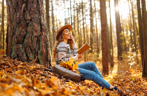 Stylish woman reading a book in the autumn park Relaxation enjoying solitude with nature