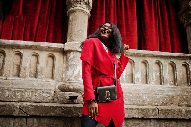 Stylish woman in red coat posed against old columns