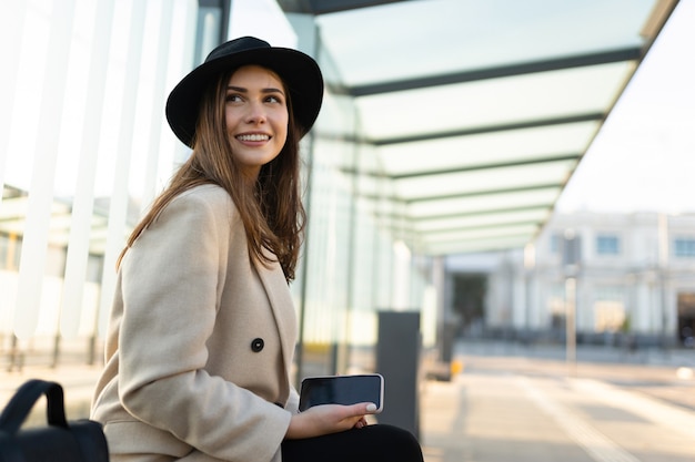 La donna alla moda si siede alla fermata del trasporto pubblico