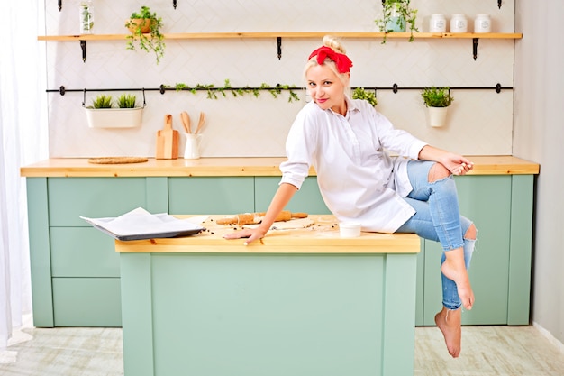 Donna alla moda che si siede sul tavolo da cucina a casa