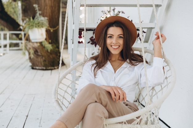 A stylish woman smiling and relaxing at a club on the beach in warm summer day