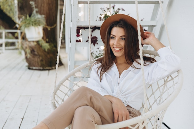 A stylish woman smiling and relaxing at a club on the beach in warm summer day