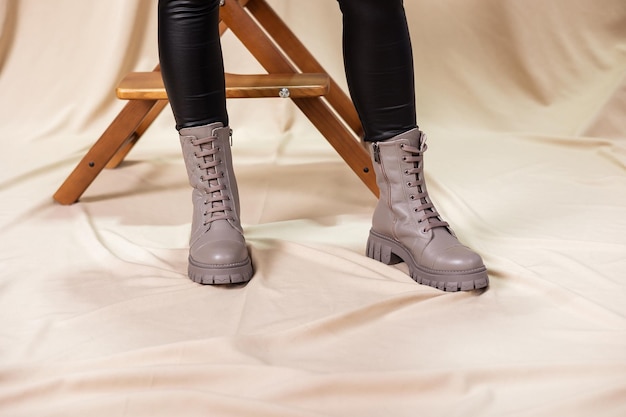 スタイリッシュな女性はベージュの靴で立っています。ファッショナブルなレザーベージュのヴィンテージブーツの女性の脚のクローズアップ。レディースシューズの新しい季節のコレクション