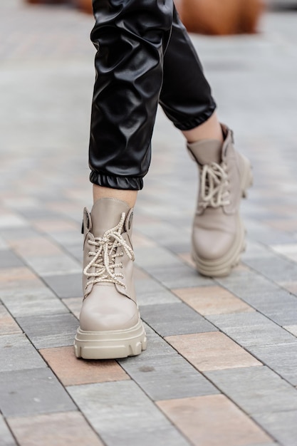 Stylish woman stands in beige shoes. Close-up of female legs in fashionable leather beige vintage boots. New seasonal collection of women's shoes