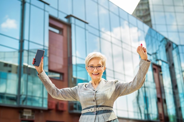 Photo stylish woman in a suit and glasses with smartphone