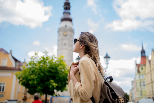 Stylish woman in sunglasses and backpack in aged city center square