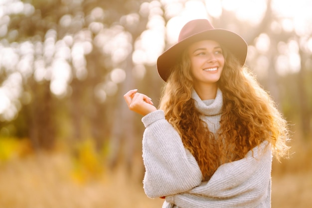 Stylish woman in sweater and hat enjoys autumn nature People freedom lifestyle travel concept