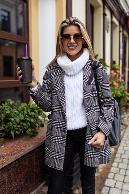 Stylish woman tourist walking around the city with a cup of coffee