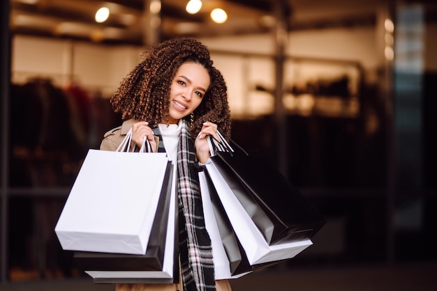 Stylish woman in trendy clothes with shopping bags near mall\
woman after shopping