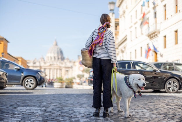 スタイリッシュな女性がローマの街を犬と一緒に歩く