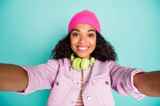 Stylish woman with afro hairstyle posing against the blue wall