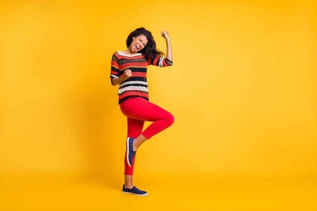 Stylish woman with afro hairstyle posing against the orange wall