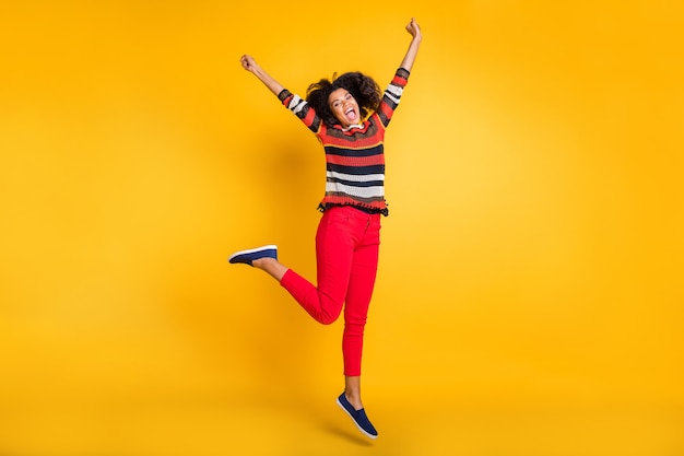 Stylish woman with afro hairstyle posing against the orange wall