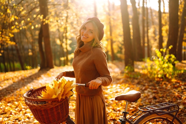 Stylish woman with bicycle enjoying autumn weather in the park Beautiful Woman in the autumn forest