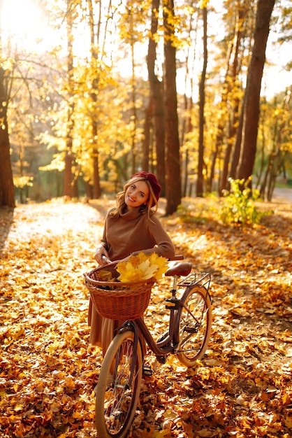 Stylish woman with bicycle enjoying autumn weather in the park Beautiful Woman in the autumn forest