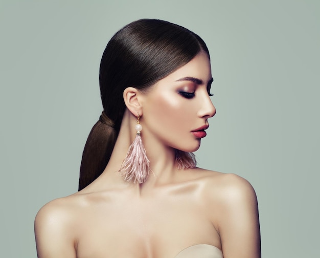 Photo stylish woman with ponytail hairstyle and pink earrings