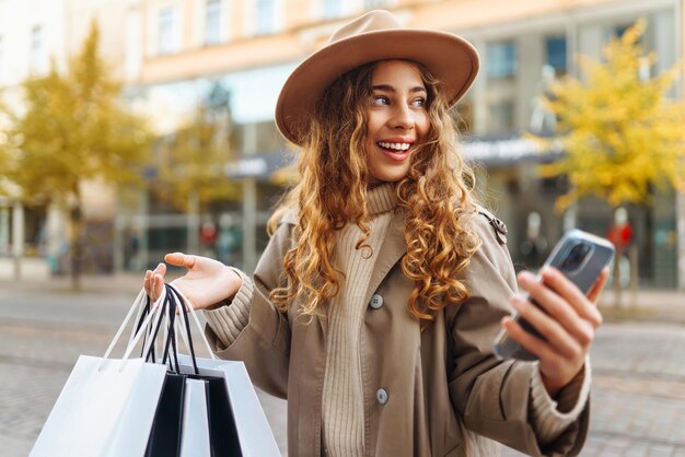 Stylish woman with shopping bags walks through city streets Consumerism shopping lifestyle concept