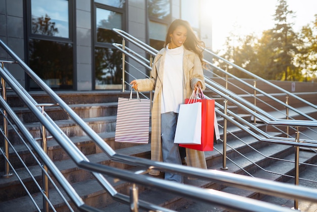 Stylish woman with shopping bags walks through city streets Purchases shopping lifestyle concept