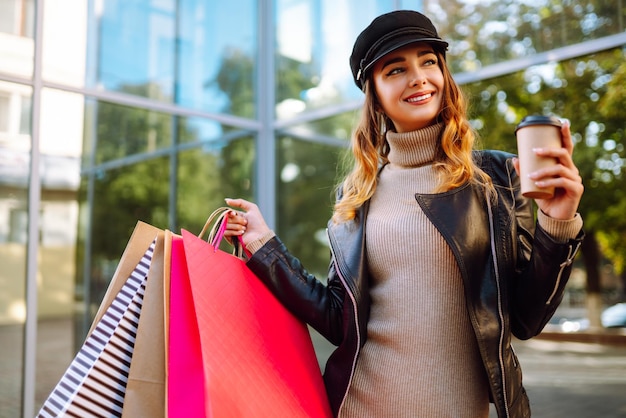 Donna elegante con le borse della spesa cammina per le strade della città in stile primavera