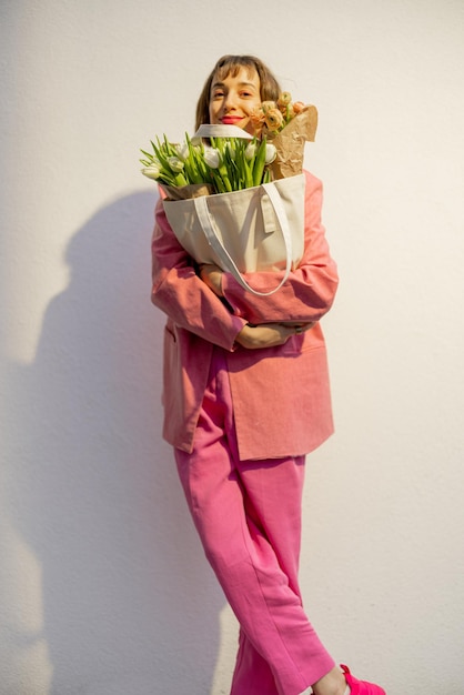 Stylish woman with tote bag and flowers on background