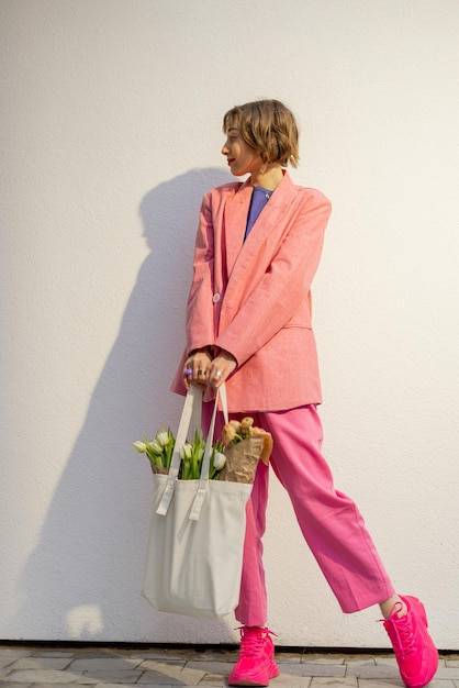 Stylish woman with tote bag and flowers on background