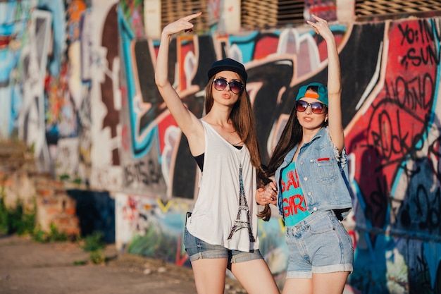 Stylish women gesturing at graffiti