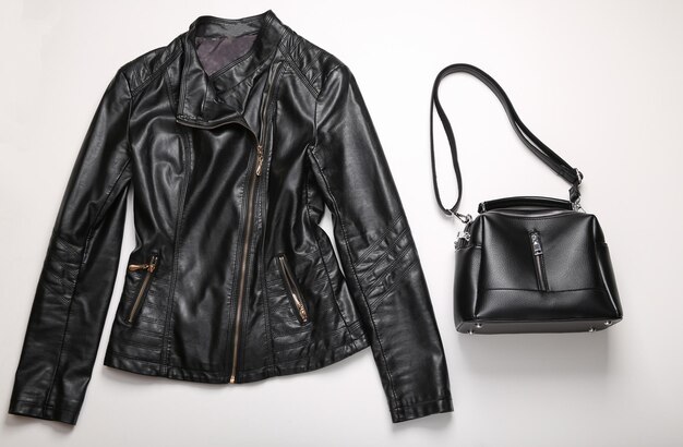 Stylish women's leather jacket and bag on white background Top view