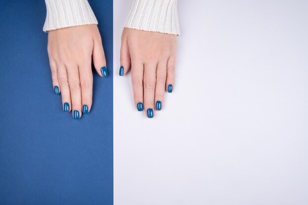 Stylish womens manicure on a blue-gray background fashionable womens manicure in blue person