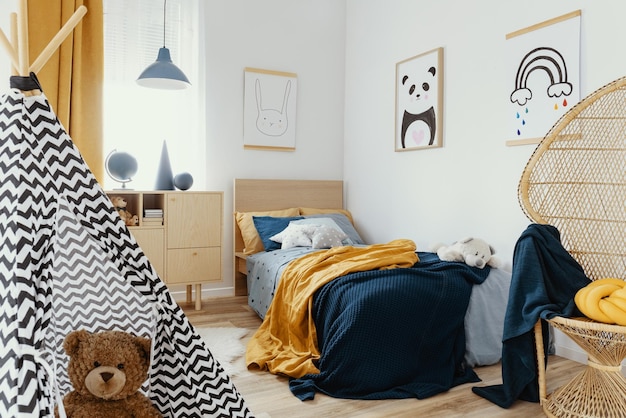 Stylish wooden commode in bright bedroom interior with poster on the wall